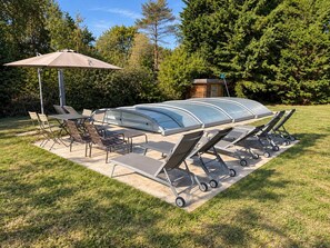 An outdoor patio with a table and chairs, a canopy, and a covered grill area.