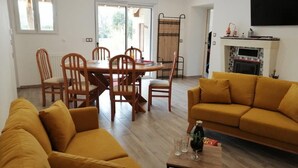 Una sala de estar con un sofá amarillo, una mesa de comedor con sillas y una chimenea.