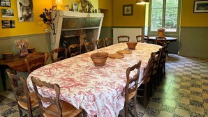A dining room with a long table, chairs, a fireplace, and a window with a view of greenery. - Historic house, pets allowed - 15 guests (Marchenoir)