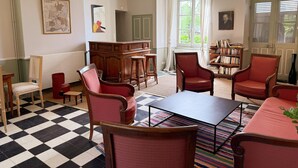 A room with a checkered floor, wooden furniture, a bookshelf, and a large window with curtains. - Historic house, pets allowed - 15 guests (Marchenoir)