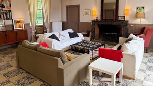A living room with a sofa, a small table, a fireplace, and a mirror. - Historic house, pets allowed - 15 guests (Marchenoir)