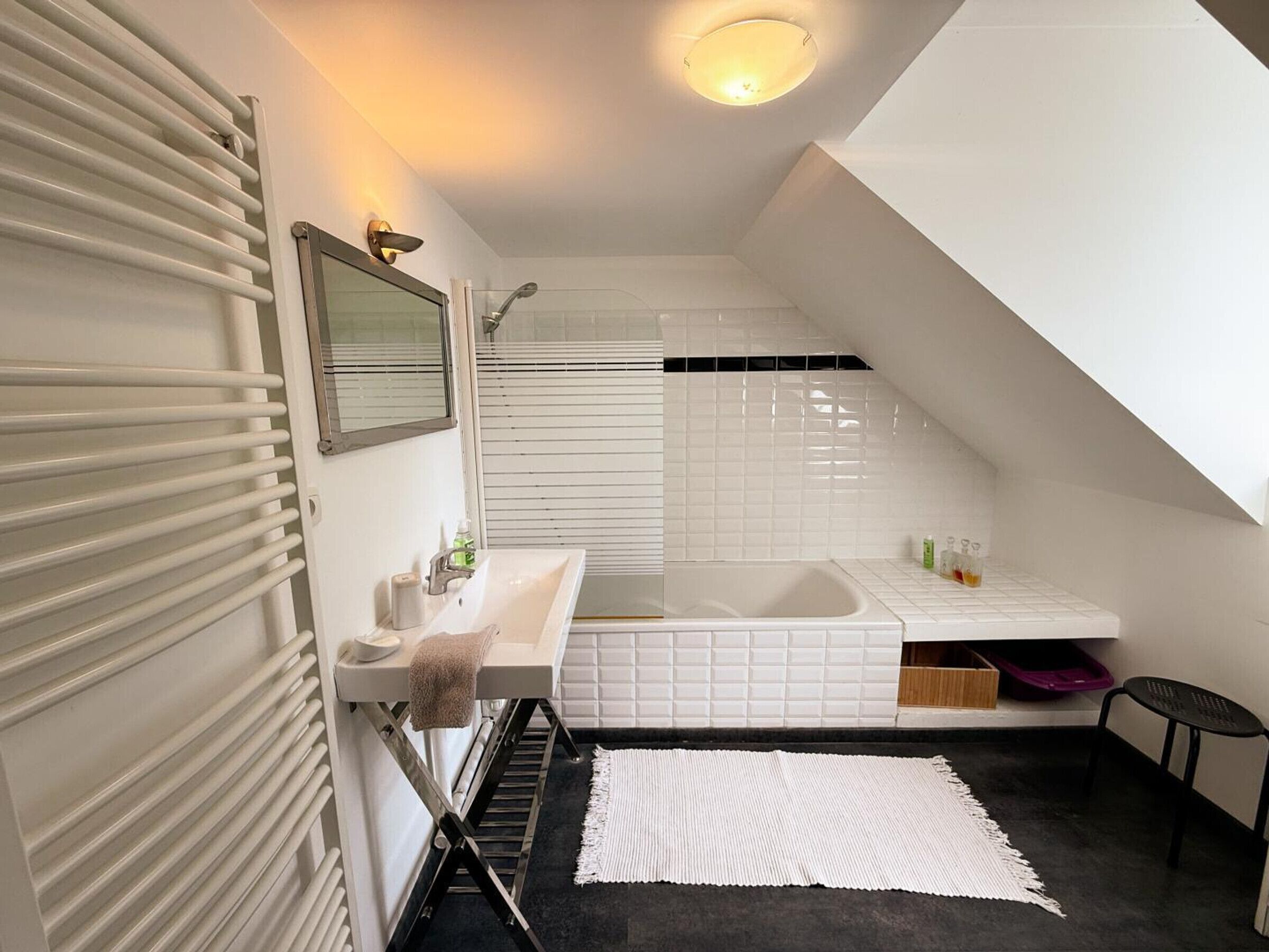 Een moderne badkamer met een wit wastafelmeubel, spiegel en douche.