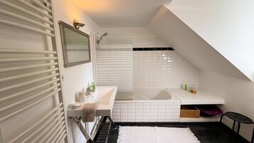 Een moderne badkamer met een wit wastafelmeubel, spiegel en douche.