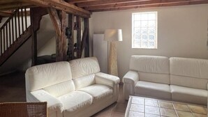 A room with a white leather sofa, a wooden staircase, a floor lamp, and a window with a view. - Charming Home near Loire Castles - Spacious, All-Inclusive, WiFi, Parking, Garden, Sleeps 8 (Vallières-les-Grandes)