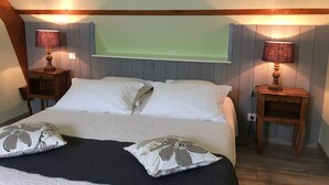 Un dormitorio con una cama, dos mesitas de noche, dos lámparas y una ventana con persianas.