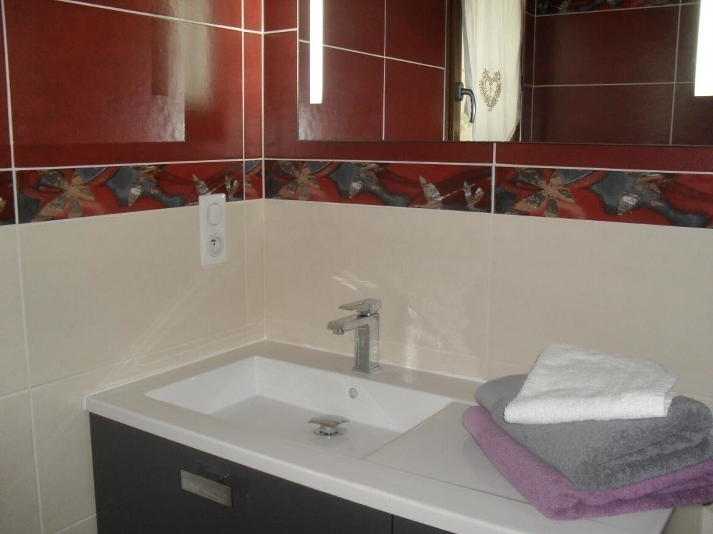 A bathroom with a white sink, a mirror, and a towel rack with folded towels.
