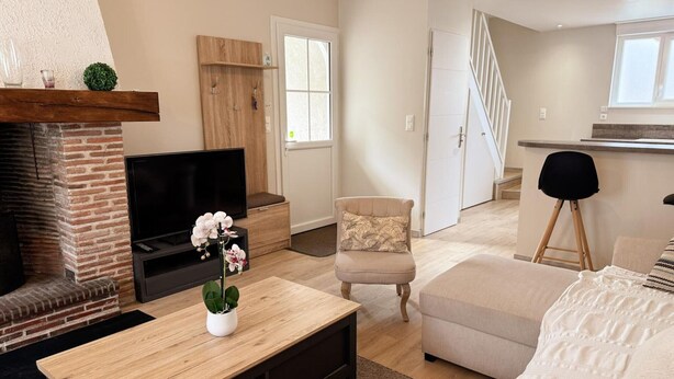A modern living room with a fireplace, a flat-screen TV, a wooden coffee table, a beige armchair, and a sofa. - Cozy Renovated Cottage in Private Courtyard near Loire Castles (Avaray)