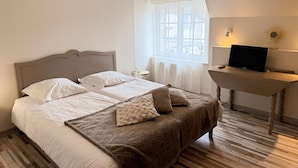 A hotel room with a double bed, a desk with a laptop, a window with curtains, and a lamp. - Cozy Renovated Cottage in Private Courtyard near Loire Castles (Avaray)