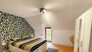 Un dormitorio con una cama, ventilador de techo, ventana y armario.