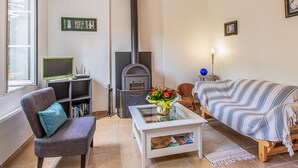 Un salon chaleureux avec une cheminée, un canapé confortable, un fauteuil, une table basse et une bibliothèque.