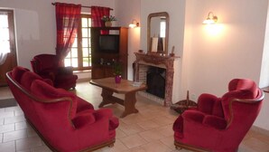 A living room with two red armchairs, a wooden coffee table, a television, a fireplace, and a mirror. - Family home in Cheverny, enclosed garden, pets allowed, 6 people (Cheverny)
