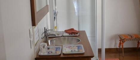 A bathroom with a wooden vanity, a mirror, a sink, and a shower area.