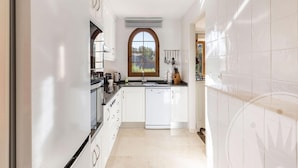 A modern kitchen with white cabinetry, a large window, and a dishwasher. - La Manga Club Monte Claro Townhouse 606 (Atamaría)
