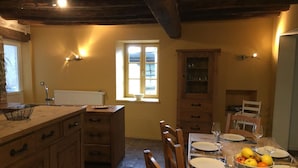 Una cocina con armarios de madera, una mesa de comedor para cuatro personas y un ventanal con vistas.