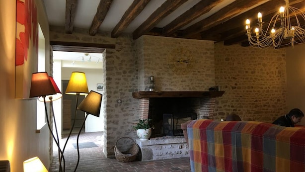 Una habitación acogedora con vigas de madera a la vista, una chimenea de piedra y una manta colorida en un sofá.