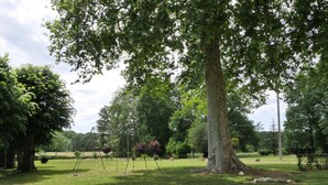 A park with a large tree, a swing set, and a grassy area. - One-story house with park near Beauval Zoo (Meusnes)