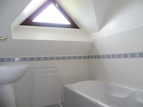 Une salle de bain équipée d’une baignoire, d’un lavabo, d’une douche et d’une fenêtre de toit.