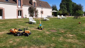 A house with a large backyard, a patio area with outdoor furniture, and a lawn. - Family Retreat with Private Pool, Games, and Farm Animals in the Countryside (Danzé)