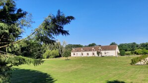A large, single-story building with a symmetrical facade, multiple windows, and a flat roof. - Family Retreat with Private Pool, Games, and Farm Animals in the Countryside (Danzé)