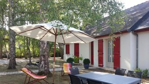 An outdoor patio with a table and chairs, a hanging chair, and a large umbrella.