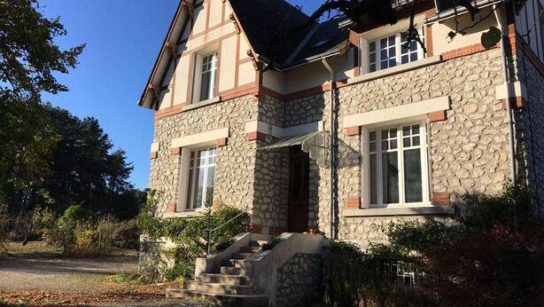 A stone house with a steep gabled roof, a front porch, and a staircase leading to the entrance. - Charming Renovated House with Garden, Near Loire Valley Castles (Dhuizon)