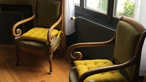 Two wooden armchairs with yellow cushions in a room with a wooden floor and a window with a view of greenery. - Charming Renovated House with Garden, Near Loire Valley Castles (Dhuizon)