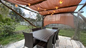 An outdoor patio with a wooden table and wicker chairs, surrounded by stone tiles. - Charming Renovated House with Garden, Near Loire Valley Castles (Dhuizon)