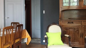 A dining area with a wooden table and chairs, a cabinet with glass doors, and a door leading to another room. - Charming Renovated House with Garden, Near Loire Valley Castles (Dhuizon)