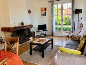 Un salon avec une cheminée, un canapé, un téléviseur et un fauteuil.