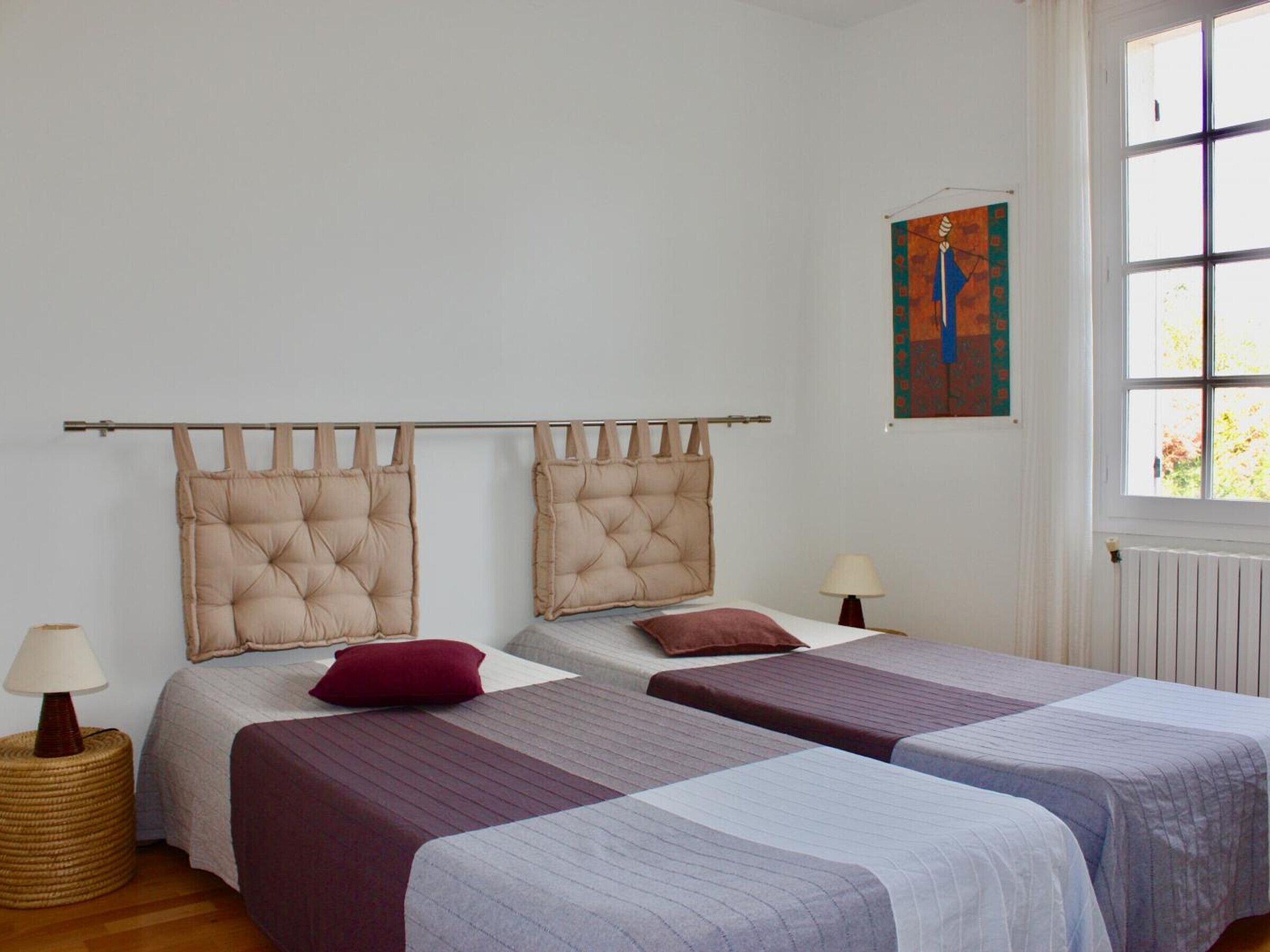 Une chambre avec deux lits, chacun doté d’une tête de lit, d’une petite table avec une lampe et d’une fenêtre avec des rideaux.