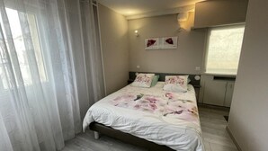 Een slaapkamer met een bed, een raam, een wandlamp en een radiator.