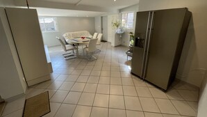 Een compacte keuken met een koelkast, een eettafel met stoelen en een klein spoelbakje.