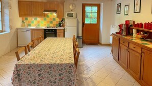 Una cocina acogedora con armarios de madera, salpicadero de azulejos, una mesa de comedor con sillas y un refrigerador.