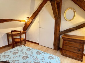 Un dormitorio con cama, cómoda de madera, una silla y una puerta.