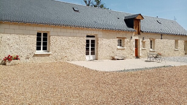 Un bâtiment en pierre doté d’un toit en pente, de nombreuses fenêtres et d’une allée gravillonnée.