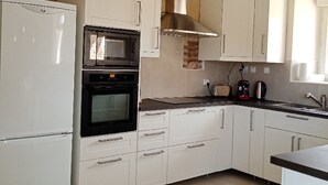 Une cuisine avec des armoires blanches, un four noir, un four à micro-ondes et une hotte de cuisinière en acier inoxydable.