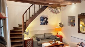 A cozy living room with a staircase, a sofa, a coffee table, and a lamp.