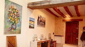 A rustic interior with exposed wooden beams, a stone wall, and a wooden counter with drawers.