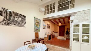 A dining area with a table and chairs, a cabinet with glass doors, and artwork on the walls.