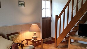 Un salon chaleureux avec un escalier en bois, une table en bois, un téléviseur et une lampe.