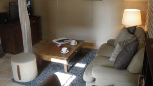 Ein gemütliches Wohnzimmer mit Couch, Holztisch, Lampe und zwei gerahmten Bildern an der Wand.