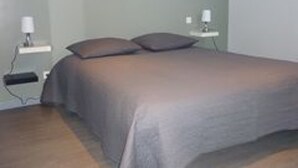 A bedroom with a bed, two bedside tables, and a wall-mounted lamp. - Modern house with large heated pool and pets allowed (Averdon)