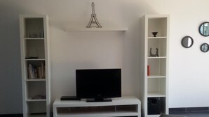 A modern living room with a flat-screen TV on a white stand, surrounded by white shelving units. - Modern house with large heated pool and pets allowed (Averdon)