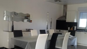 A modern dining area with a table set for six, surrounded by white chairs. - Modern house with large heated pool and pets allowed (Averdon)