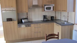 A compact kitchen with wooden cabinets, a built-in microwave, a toaster, and a coffee maker.
