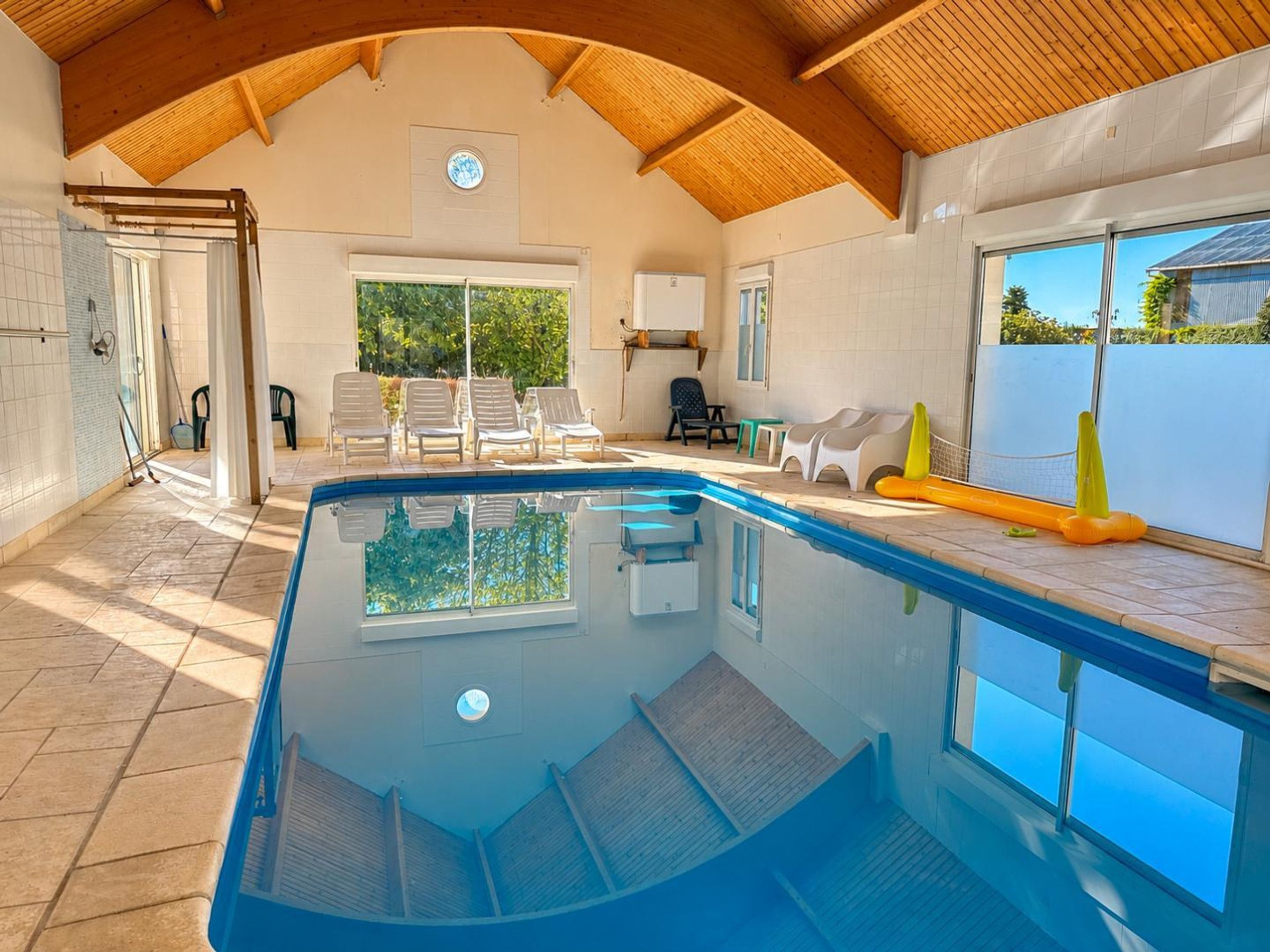 Une piscine dotée d’un plafond en bois et offrant une vue sur l’extérieur.