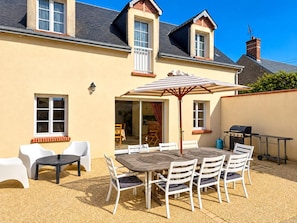 A two-story house with a patio area featuring a table and chairs, a grill, and a covered seating area. - House with private heated pool, pets allowed near Loire castles (La Chapelle-Saint-Martin-en-Plaine)