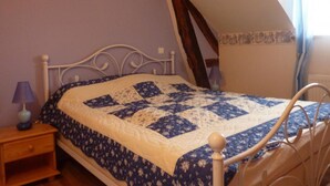 Un dormitorio con una cama, una mesita de noche, una lámpara y un cuadro en la pared.