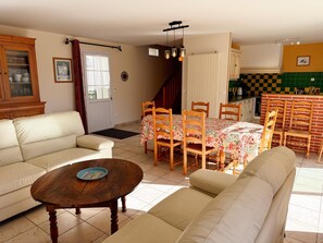A living room with a sofa, a coffee table, a dining table with chairs, a kitchen area with a checkered backsplash, and a staircase. - House with private heated pool, pets allowed near Loire castles (La Chapelle-Saint-Martin-en-Plaine)