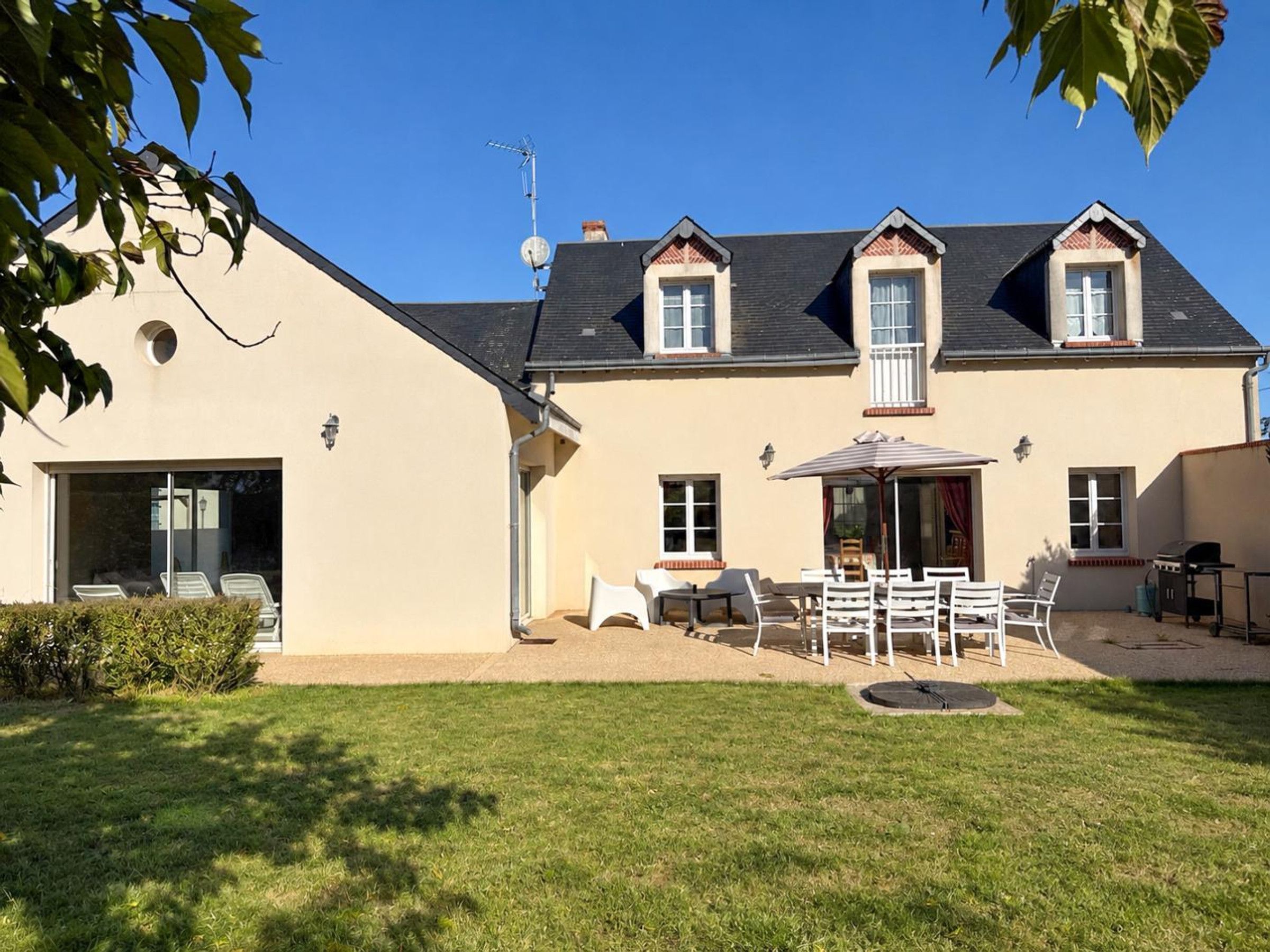 Een tweelaags huis met een terras, een barbecue en een overdekte zithoek.